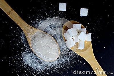 spoons with crumbly sugar and raffinate on a black background Stock Photo