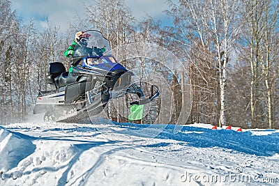 Sport blue snowmobile jump. Sunny winter day with blue sky. Concept quick movement. Stock Photo