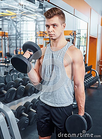 Sport, bodybuilding, training and people concept - young man with dumbbell flexing muscles. men working with dumbbells his body at Stock Photo