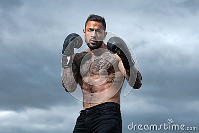 Sport boxing. Sportsman boxer fighting on sky background. Strong athletic man with boxing gloves punching. Muscular Stock Photo