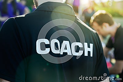 Sport coach in black shirt with white Coach text on the back sta Stock Photo