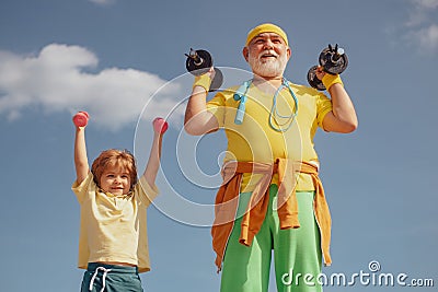 Sport exercise for kids. Lifting dumbbells. Portrait of senior man and cute child lifting dumbbells. Grandfather and son Stock Photo