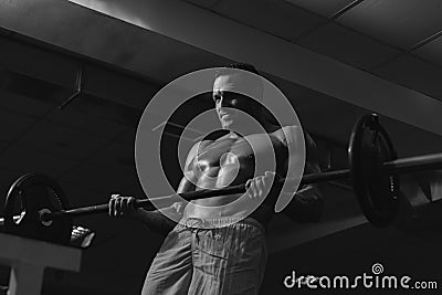 Sport exercises. Bodybuilder man with bar in gym. Sportsman with naked torso. Sporty workout. Stock Photo