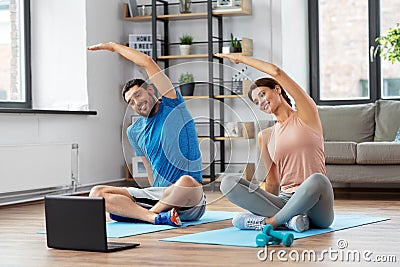 Happy couple with laptop exercising at home Stock Photo