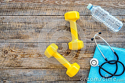 Sport and health. Fitness. Dumbbells and stethoscope on wooden background top view copyspace Stock Photo