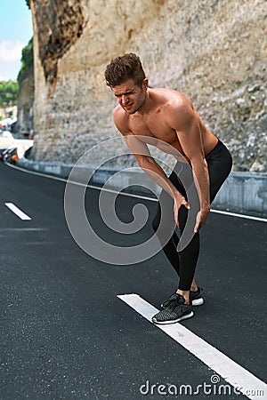 Sport Injury. Man Injured Leg During Running Outdoors. Knee Pain Stock Photo