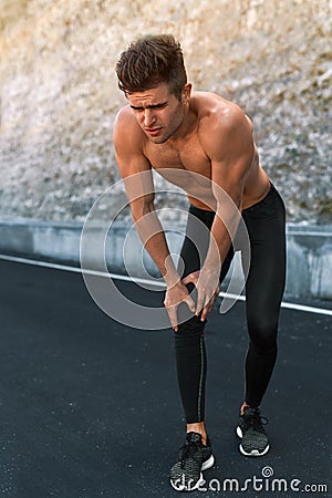 Sport Injury. Man Injured Leg During Running Outdoors. Knee Pain Stock Photo