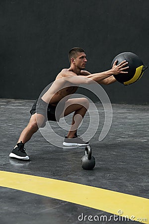 Sport man doing side lunge exercise with med ball at fitness gym Stock Photo