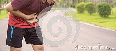 Sport man holding abdomen with his hands in stomach pain after running workout at park. Health care concept Stock Photo