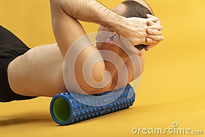 Sport man using myofascial roller for muscle and fascia stretching back on yellow background. Handsome man doing exercises with Stock Photo