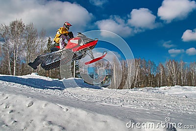 Sport red snowmobile jump. Sunny winter day with blue sky. Concept quick movement. Stock Photo