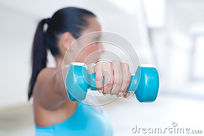 Sport woman with blue dumbbell doing exercise outdoor, only dumb bell and hand in focus Stock Photo