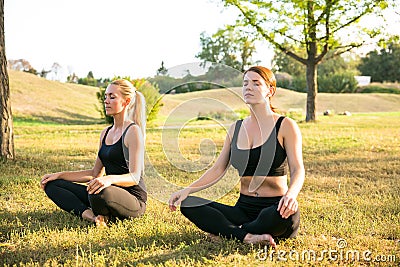 Sport women doing yoga outside in morning. Fitness girls relax in park Stock Photo