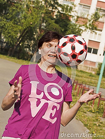 Sporting an old woman enthusiastically tries to catch ball thrown to her.Playing football. Stock Photo