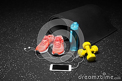 Sportive accessories for gym training. Sport shoes, dumbbells, bottle, and smart phone on a black background. Copy space Stock Photo