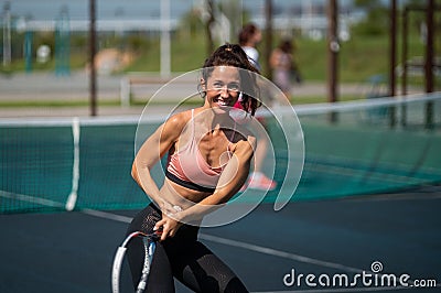 Sportive caucasian woman posing with a racket on a tennis court outdoors. Stock Photo