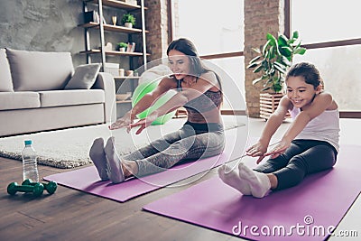 Sportive family concept. Adorable excited cheerful joyous beautiful step-sisters are doing sport limbering up together, they are Stock Photo