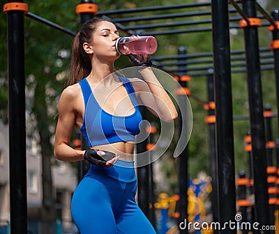 Sportive woman drinking vitamin water at the street gym Stock Photo