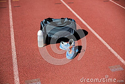 Sports bag, shoes and a water bottle kept on a running track Stock Photo