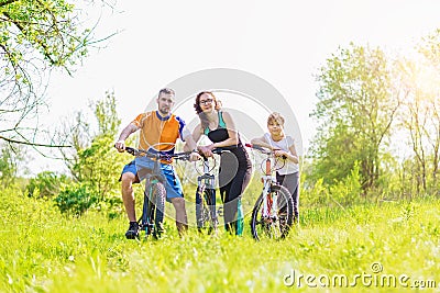 Sports family: mom, dad and daughter are standing with bicycles in nature Stock Photo