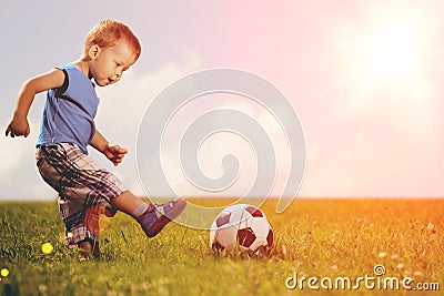 Sports kid. Boy playing football. Baby with ball on sports field Stock Photo