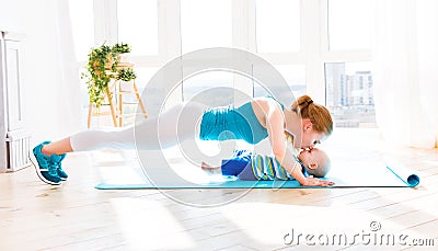 Sports mother is engaged in fitness and yoga with baby at home Stock Photo