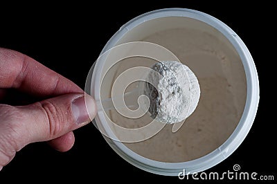 Sports Nutrition Powder. Soluble creatine in a measuring spoon in the hand to increase muscle mass and strength. On a black Stock Photo