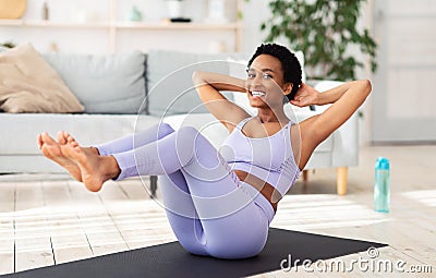 Sports during quarantine. Attractive black woman doing fitness on sports mat at home, exercising her abs muscles Stock Photo