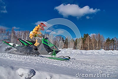 Sports snowmobile is rushes at high speed from slope. Green car for extreme winter sports. Concept quick movement. Stock Photo