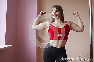 Sports strong girl bodybuilder shows biceps and smiles, woman with big muscles Stock Photo