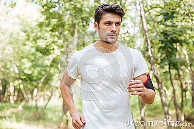 Sportsman with handband running in forest in the morning Stock Photo