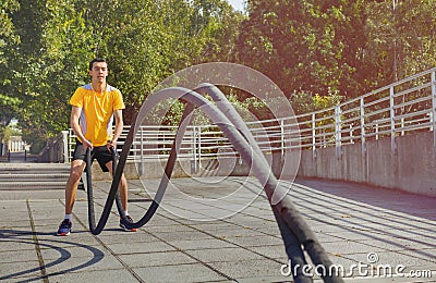 Sportsman making wave movement with battle rope Stock Photo