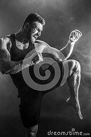 Sportsman muay thai boxer fighting on black background with smoke. Stock Photo