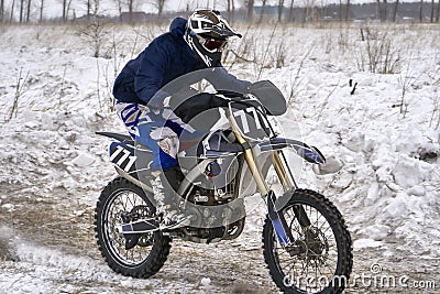 Sportsman racer man fulfills a fast ride on a motorcycle on the road extreme. The race track is very uneven. Stock Photo