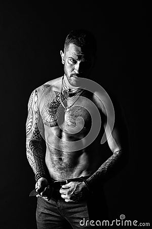 Sportsman with six pack and ab. Fashion model buckle leather belt in jeans. Man with tattoo design on skin. Bearded man Stock Photo