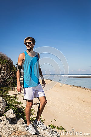 sportsman in sunglasses standing on rocks on seashore Stock Photo