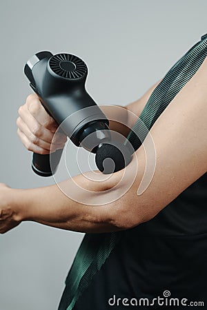 Sportsman uses a massage gun on his arm Stock Photo