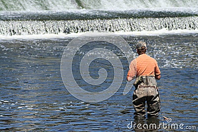 Sportsman in Waders Fishing at Dam Stock Photo