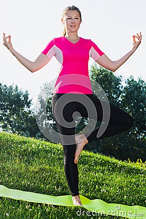 Sportswoman in pink T-shirt is staying and practising meditation Stock Photo