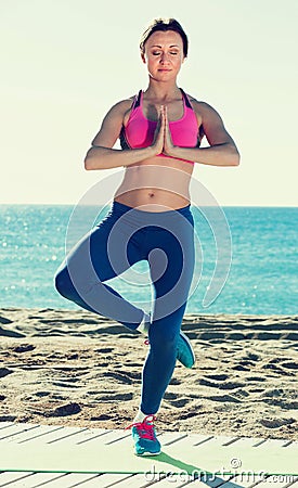 Sportswoman practices asanas of yoga on beach Stock Photo