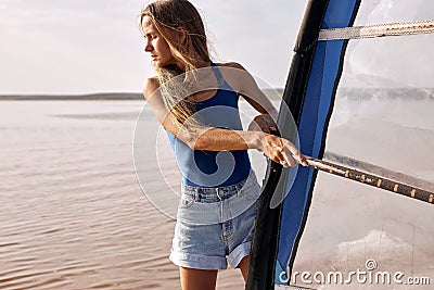 sportswoman stands on windsurf and holds the sail. Windsurfing on lake water, relaxing on water Stock Photo