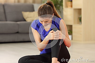 Sportswoman suffering knee ache at home Stock Photo