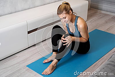 Sportswoman suffering knee ache sitting on the floor in the living room Stock Photo