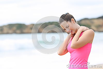 Sportswoman suffering neck ache on the beach Stock Photo