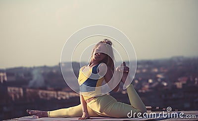 Sporty beautiful girl doing yoga in yellow sportswear under morning. Stock Photo