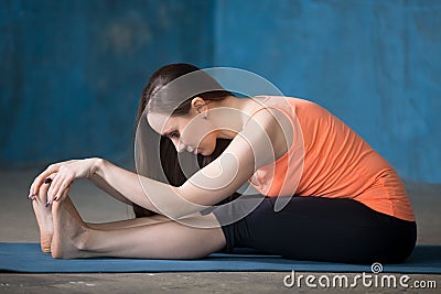 Sporty beautiful young woman doing Paschimothanasana Stock Photo