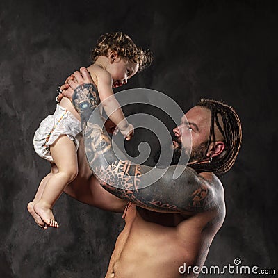Sporty brutal man holds in arms a little baby Stock Photo