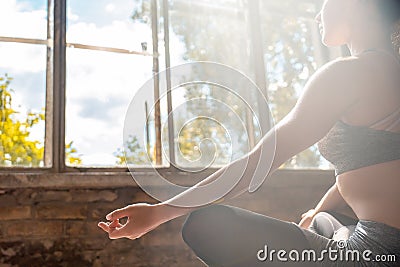 Sporty calm woman sit in lotus pose doing yoga meditating in sunny gym Stock Photo