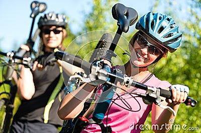 Sporty couple carrying their mountain bikes Stock Photo