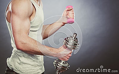Sporty fit man lifting light and heavy dumbbells. Stock Photo